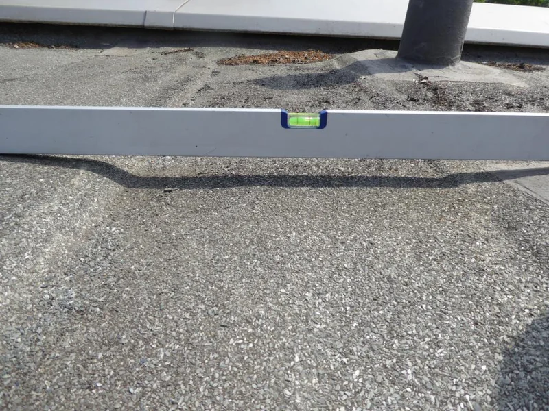 Wasserwaage auf einer Dachfläche neben einem Rohranschluss